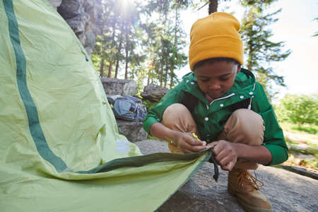African little boy setting up the tent during camping in the natureの写真素材