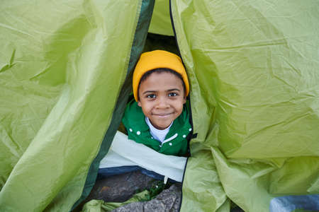 Portrait of African little boy sitting in tent and looking at cameraの写真素材