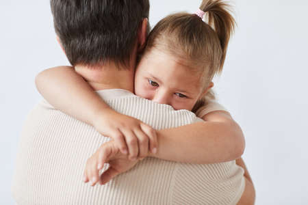 Little girl embracing and loving her father against the white backgroundの写真素材