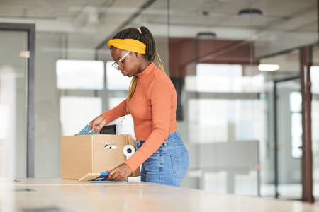 African young woman unpacking the box with stuffs she getting a new job at officeの写真素材