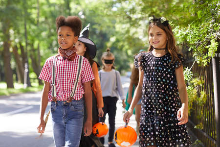 Group of children in Halloween costumes walking together along the streetの写真素材
