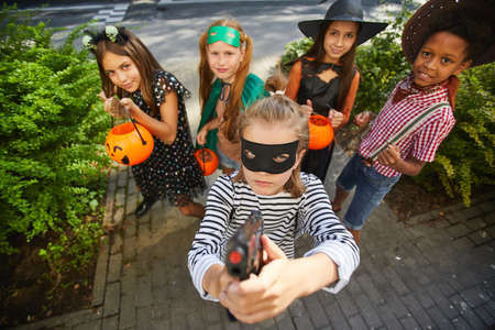 Group of children in Halloween costumes playing trick or treat during holiday they standing outdoors and smiling at cameraの写真素材
