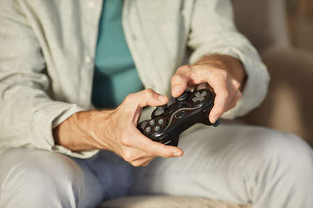 Close-up of young man pushing buttons on joystick during play in computer game