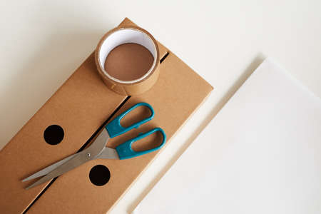 High angle view of cardboard box with adhesive tape and scissors on it isolated on white backgroundの写真素材