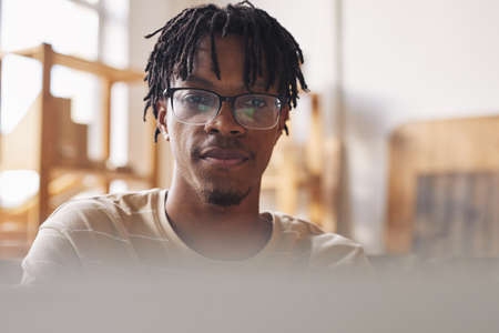 African young man in eyeglasses typing on laptop computer he working online at work