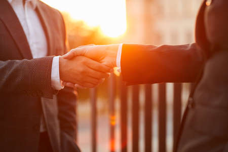Close-up of business people in formal suits shaking hands to each other during meeting standing at...