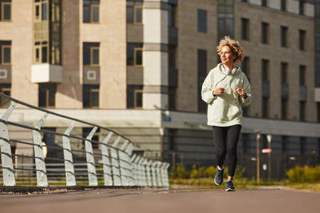 Young healthy woman in sports clothing jogging along the street in the cityの写真素材