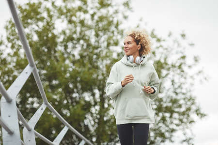 Young woman with curly hair jogging alone in the park outdoors