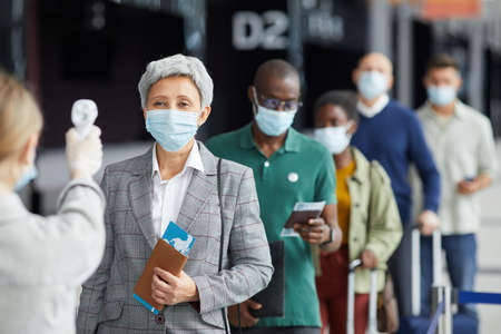 Group of people in mask standing in a row and testing they are at the airportの写真素材