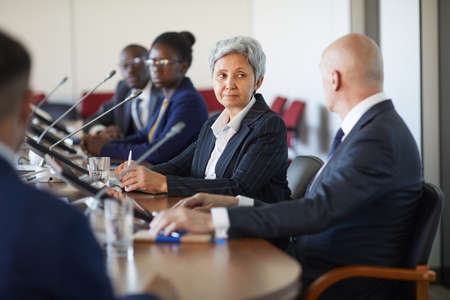 Business people sitting at the table and talking to each other during business conference