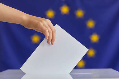 Close-up of woman putting the envelope into the box she voting for new presidentの写真素材