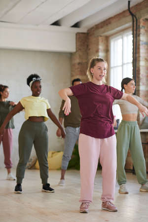 Young woman working as a instructor and training her group in dance hall