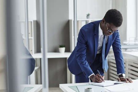 African young businessman planning his business in note pad at the table at office