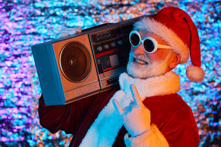 Excited Santa Claus in sunglasses listening to music on stereo and dancingの写真素材