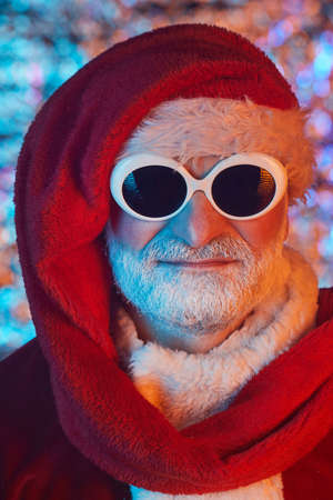 Close-up of senior man dressed as a Santa wearing sunglasses and hat looking at cameraの写真素材