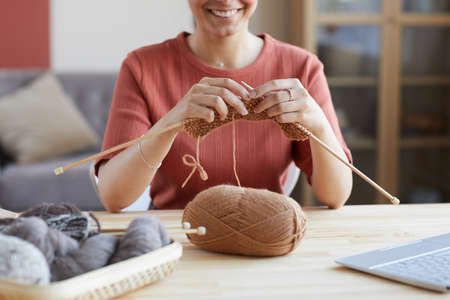 Close-up of young woman sitting at the table and knitting at homeの写真素材