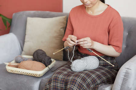 Close-up of woman resting on sofa and knitting the scarf at home