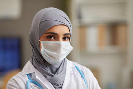 Close-up of muslim female doctor in protective mask looking at camera working at hospitalの写真素材