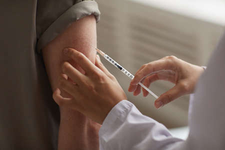 Close-up of doctor with syringe giving an injection in patients shoulder at hospitalの写真素材