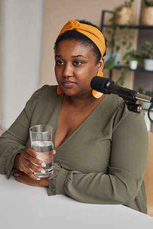 African elegant woman drinking water before her interview on the radio
