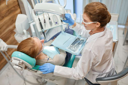 Dentist using medical instruments during dental procedure with patient at clinicの写真素材