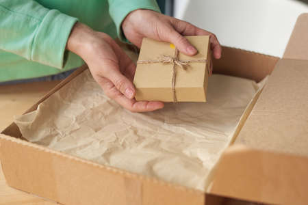 Close-up of woman holding packed little box while opening her parcel