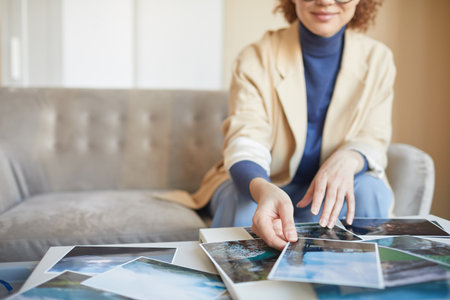 Close-up of female designer sitting in front of the table and working with professional picturesの写真素材