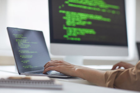 Close-up of developer developing new program while typing on laptop at the table at officeの写真素材