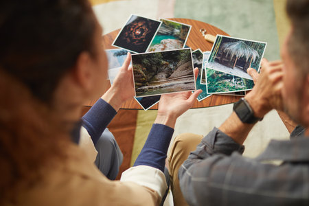Rear view of young couple looking at their photos and remembering happy moments