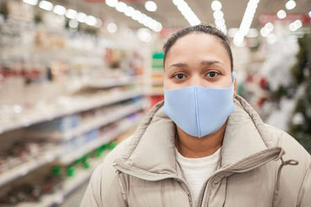 Close-up of woman wearing protective mask looking at camera while standing in the store
