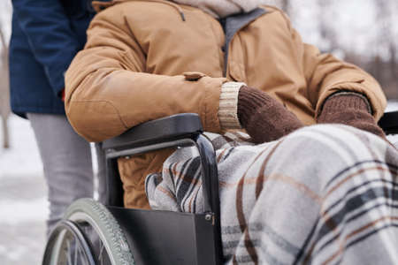 Close-up of African man sitting in wheelchair covering with warm blanket during his winter walkingの写真素材