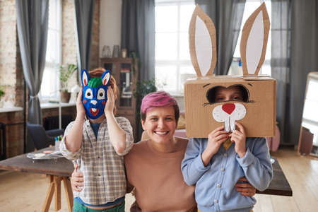 Portrait of mother embracing her two children in rabbit costumes they preparing for Easter holiday