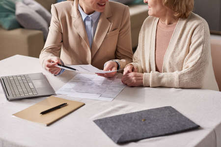 Close-up of businesswoman giving a consultation to senior woman about financial documents during...