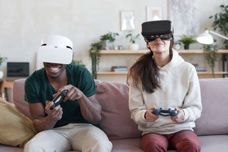 Couple playing in team while sitting on sofa