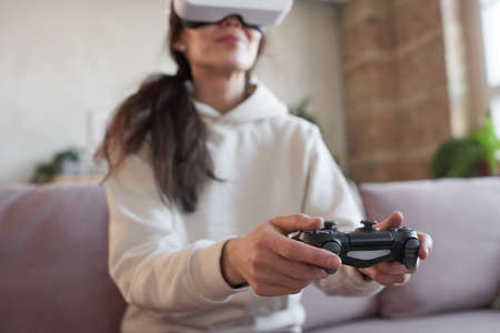 Woman using joystick in game sitting on sofaの写真素材