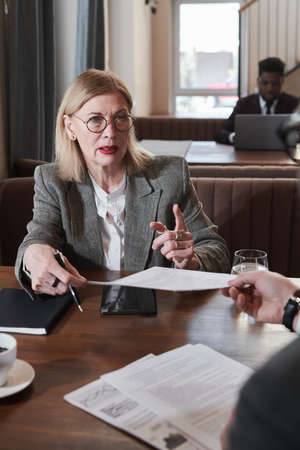 Mature businesswoman consulting the man about documents during meeting in cafe