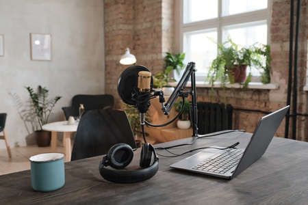 Image of workplace with laptop microphone and headphones in modern office of radio studioの写真素材