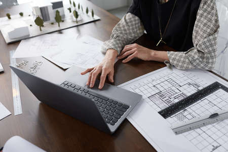 Close-up of architect typing on laptop at the table and developing new project of building working at officeの写真素材