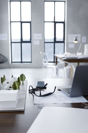 Image of workplace of architect with model of new building and blueprints at officeの写真素材