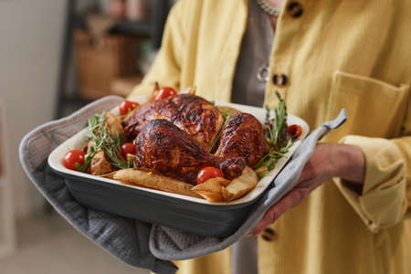 Close-up of senior woman holding dish with roasted chicken and vegetablesの写真素材