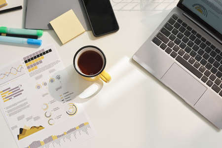 High angle view of cup of coffee on the table with laptop and documents on it at officeの写真素材
