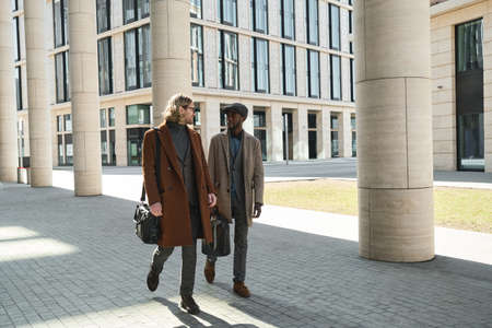 Two young men walking along the street in the city in sunny day