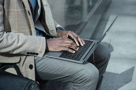 Close-up of African businessman working on laptop online outdoorsの写真素材