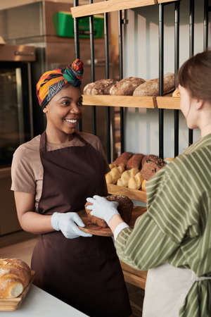 Two young women with bread working in the bakeryの写真素材