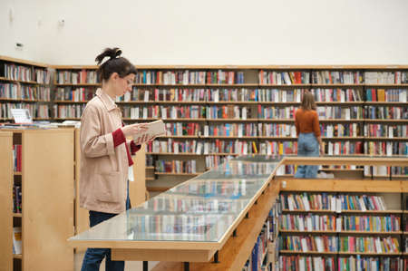 Young people studying in the library and choosing books for readingの写真素材