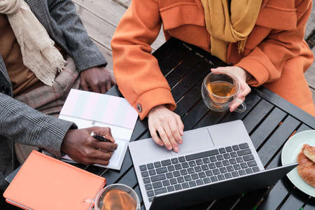 Close-up of business people sitting at the table drinking tea and working on laptopの写真素材