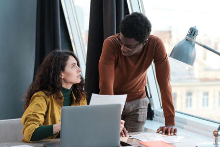 Young businesswoman discussing business documents with her colleague during their work at office