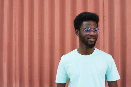 African young man in eyeglasses and in white shirt standing outdoorsの写真素材
