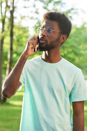 African young man talking on mobile phone while standing outdoorsの写真素材