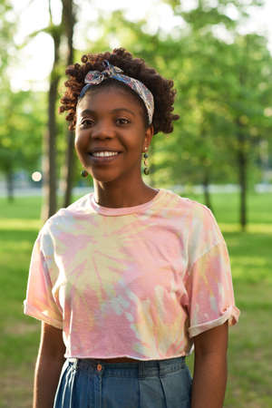 Portrait of African young woman smiling at camera while standing in the park
